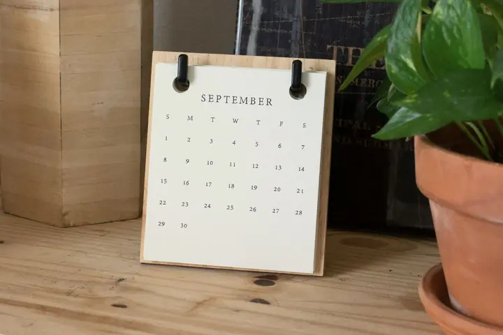 Bordskalender på en träskiva bredvid en krukväxt